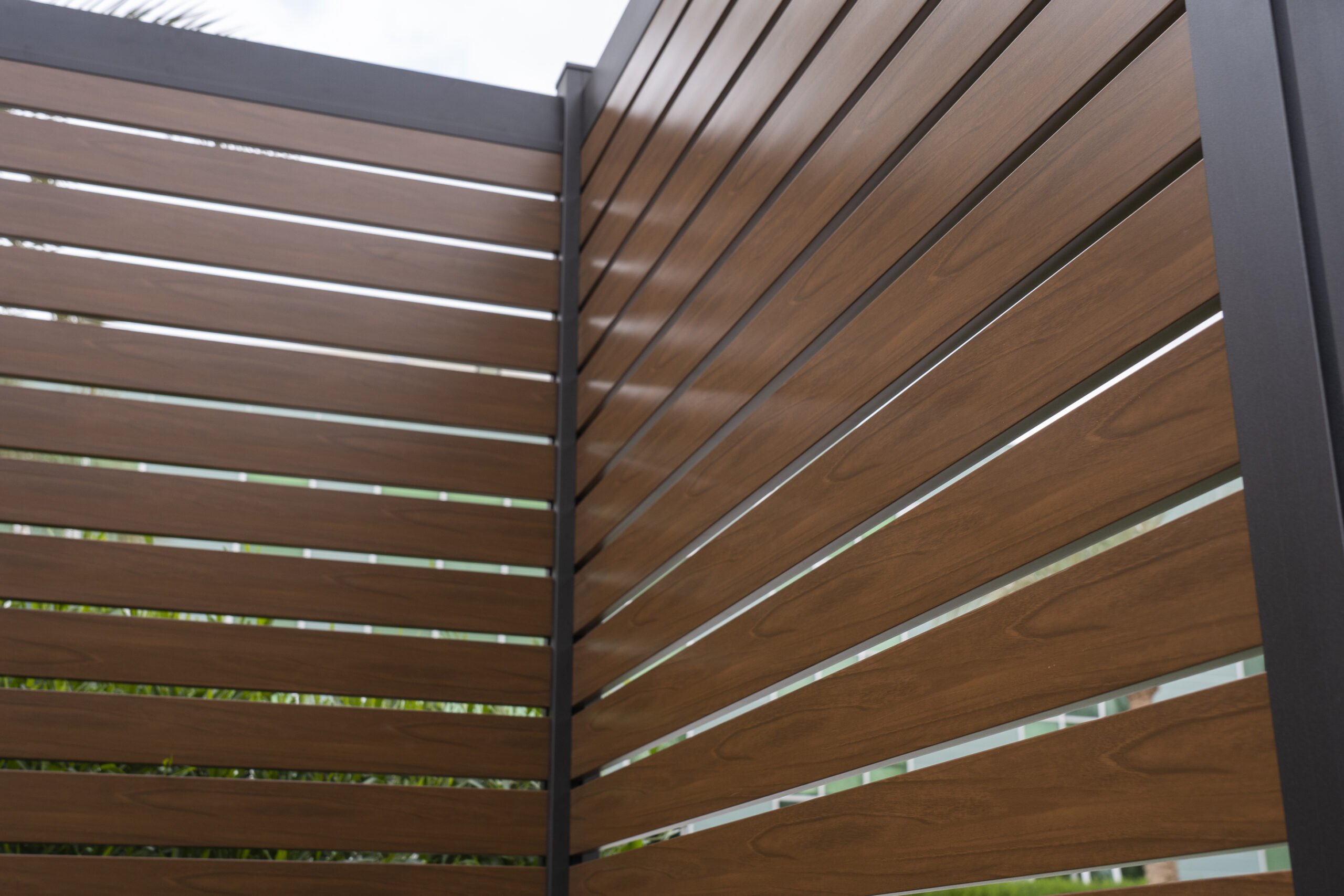 PrimeAlux aluminum fence with rich wood-grain finish.