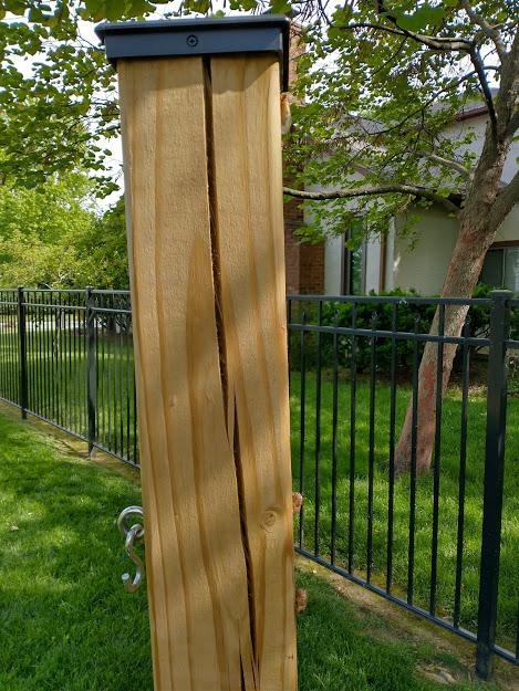 Cracked wooden fence post showing how exposed end-grain fails when the post cap separates or splits