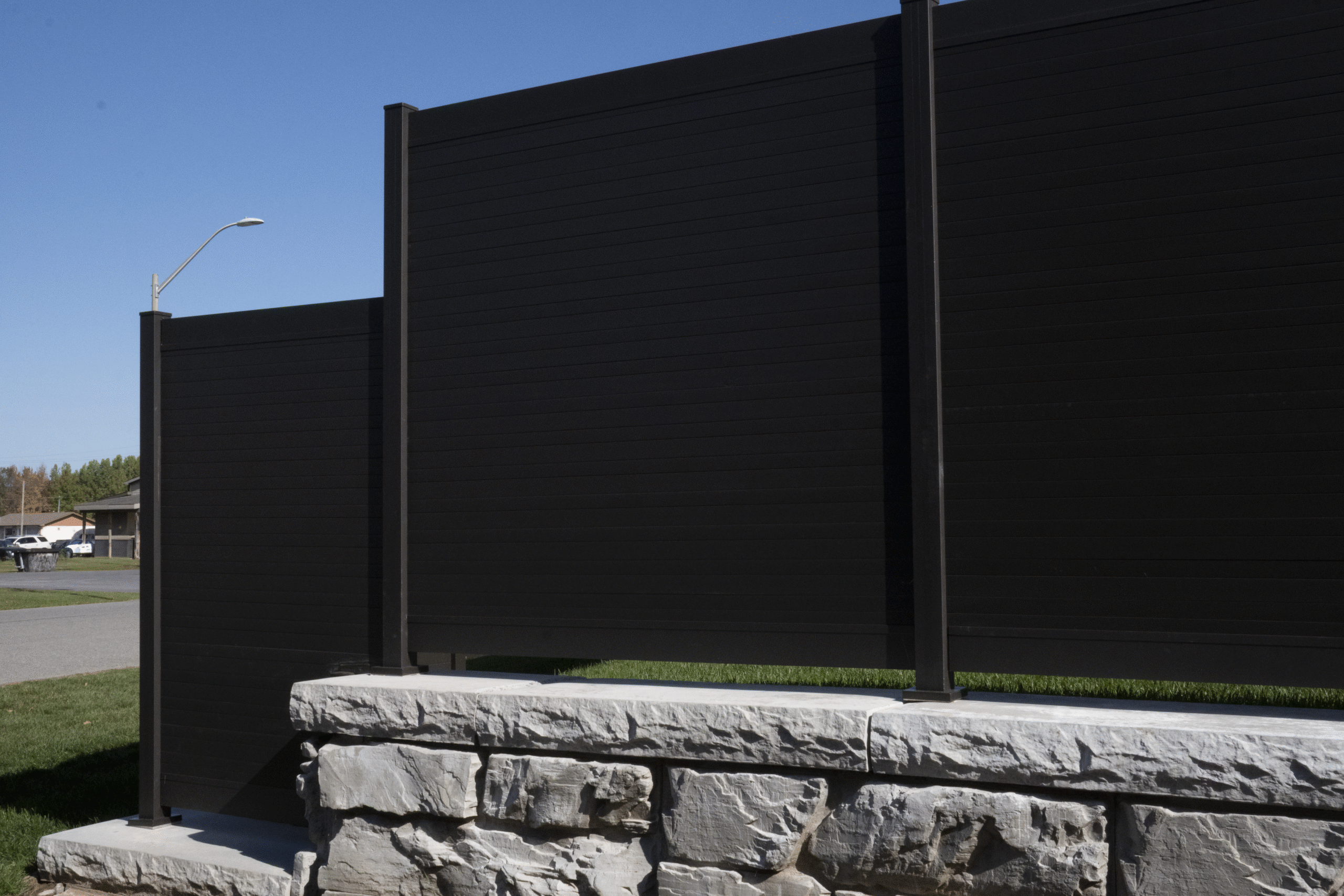 Close-up of PrimeAlux aluminum fence panel installation showing post anchor, top rail and privacy slat alignment