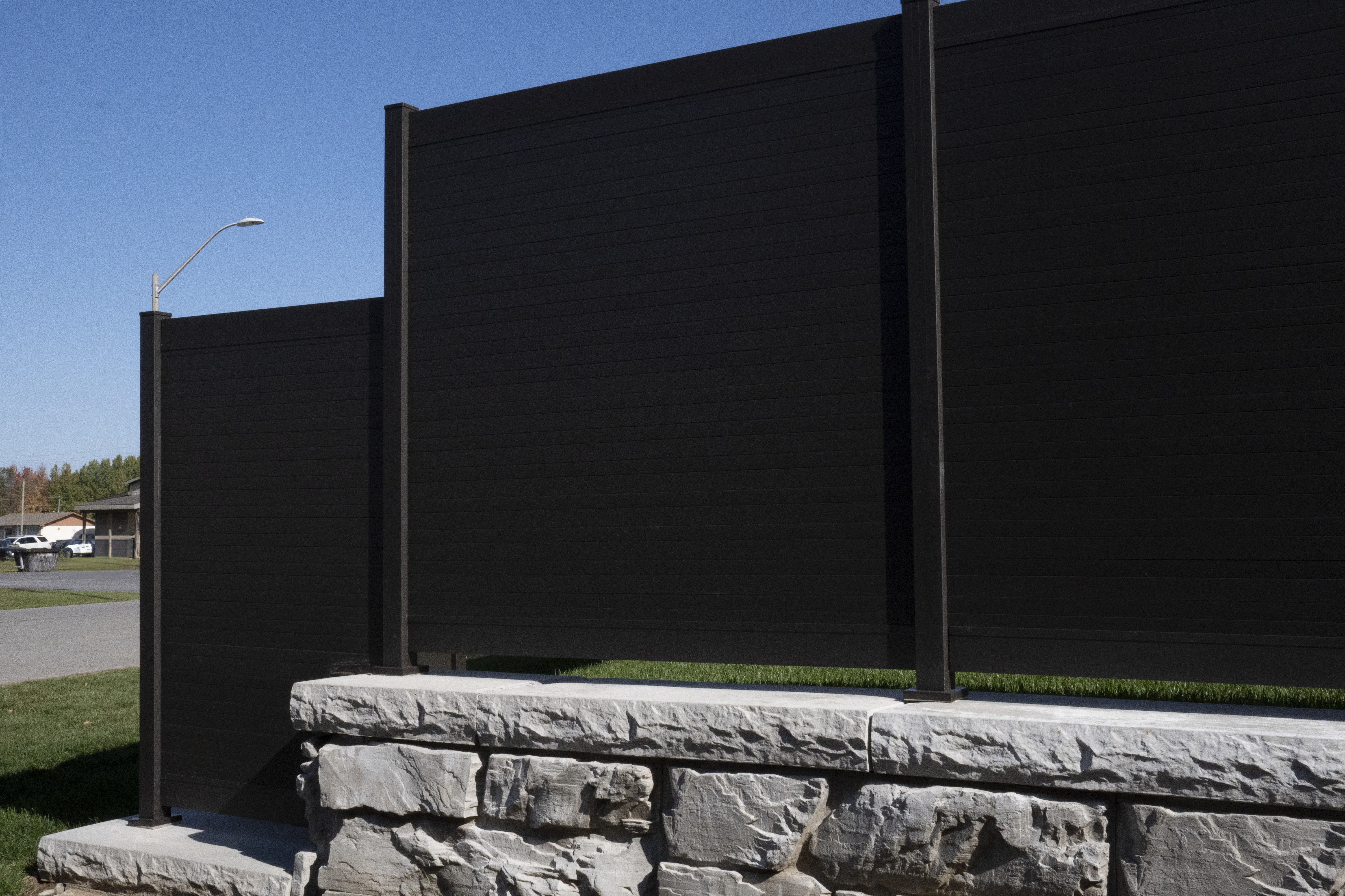 Close-up of PrimeAlux aluminum fence panel installation showing post anchor, top rail and privacy slat alignment