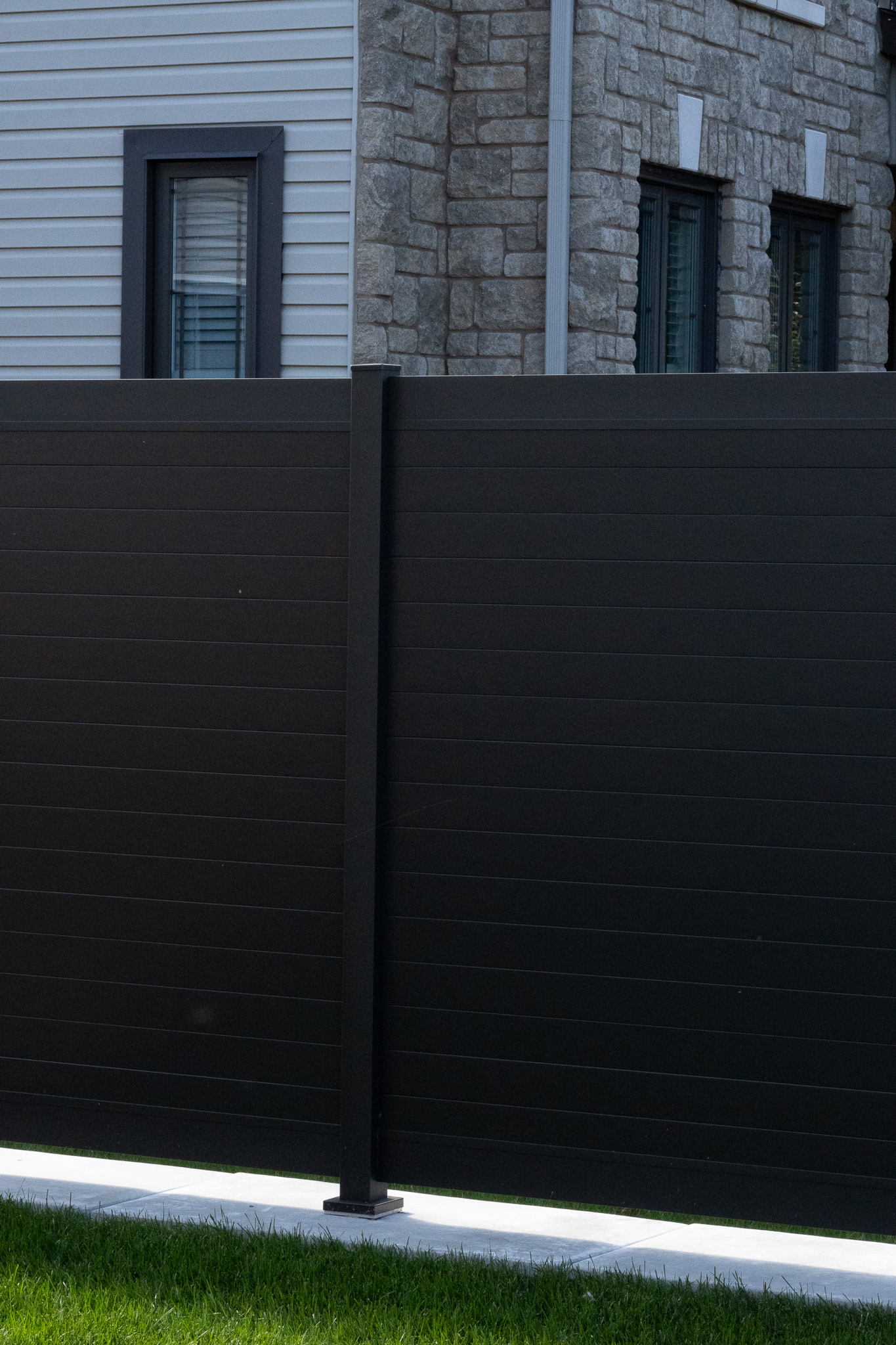 PrimeAlux aluminum privacy fence installed along a residential backyard property line, showing full fence run and post alignment