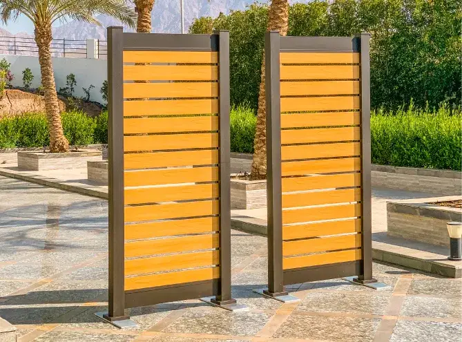 Two wooden panels stand on a stone surface, in a charming semi privacy configuration; spacing between the pickets.