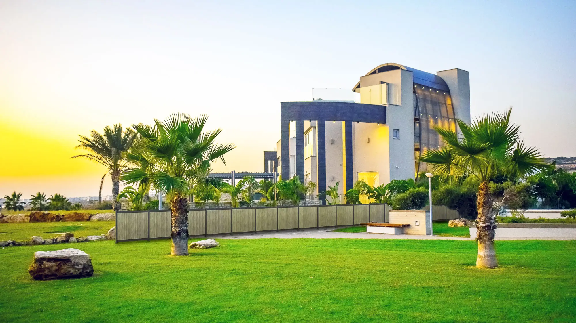 Modern looking building with a fence and palm trees