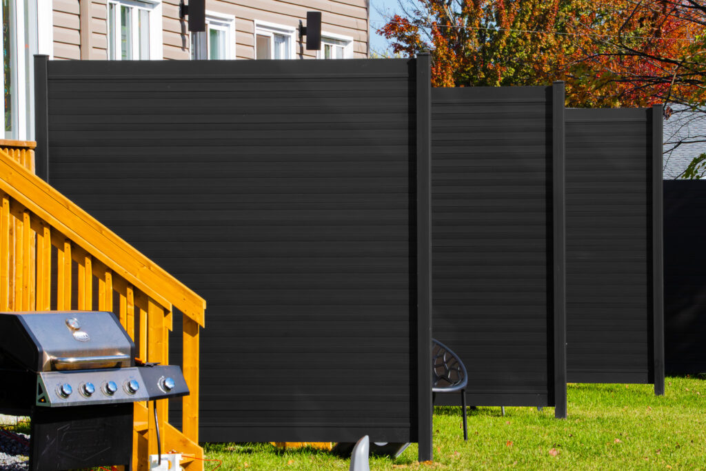 Modern black aluminum fence panels installed in a residential backyard with sleek horizontal slats