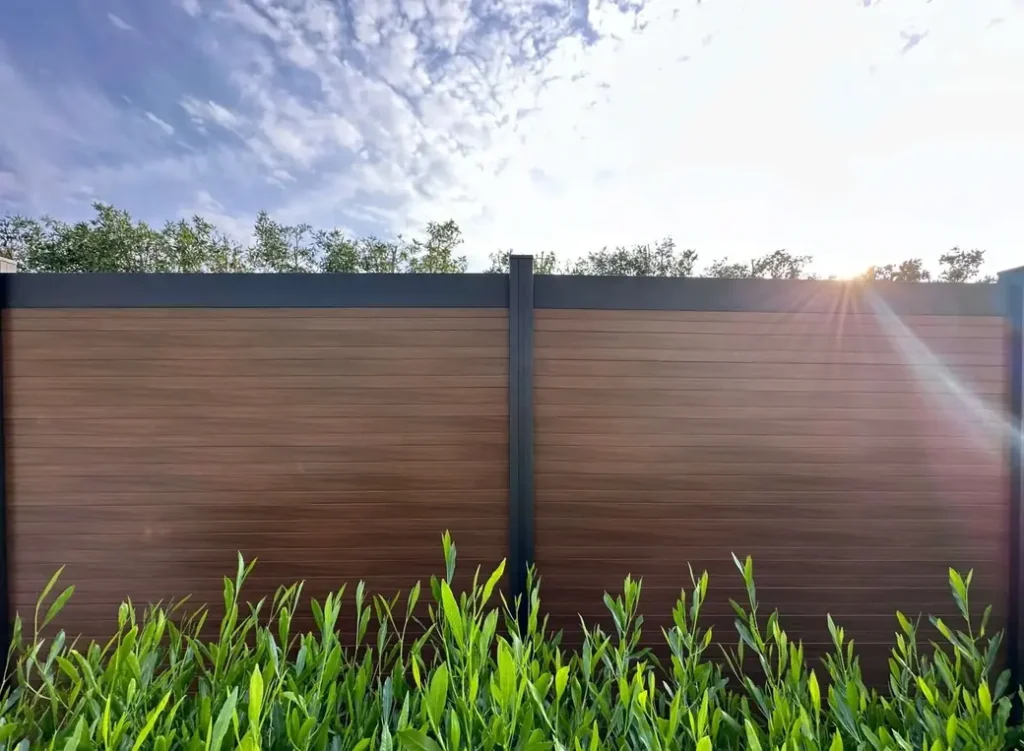 wood looking aluminum privacy fence with greens and a bright sun