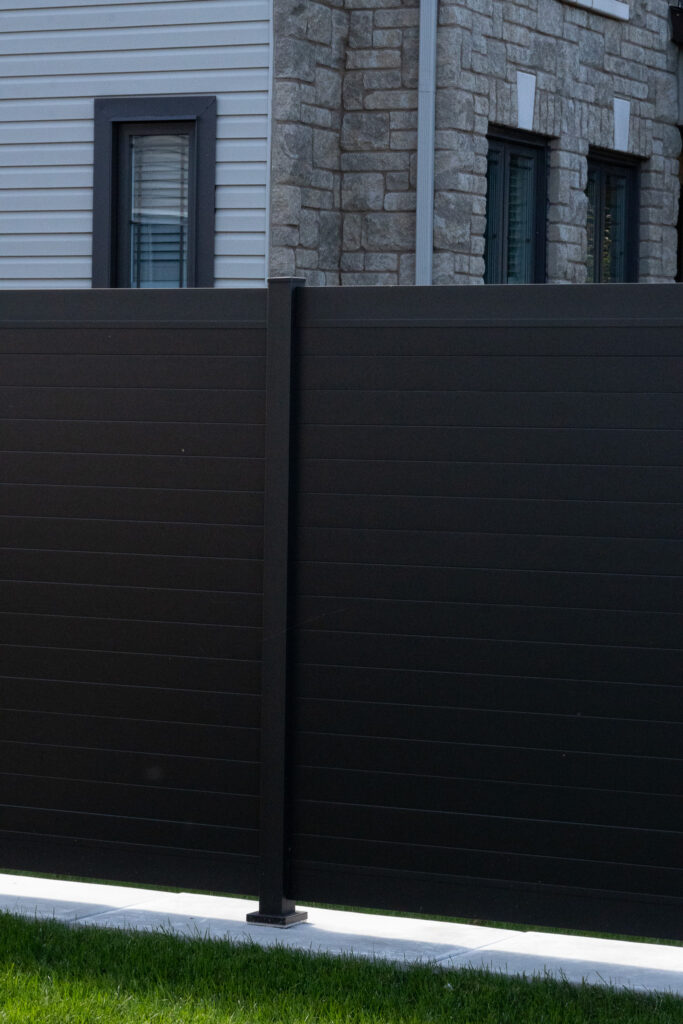 a black aluminum fence with a multi unit house building behind