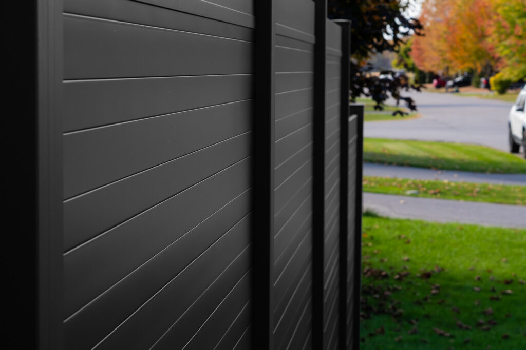 a black privacy fence photograph with beautiful greens in the background